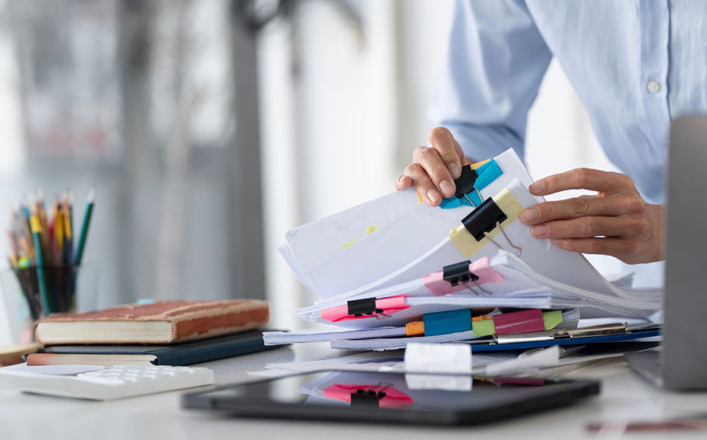 Businesswoman hands working in Stacks of paper files for searching and checking unfinished document achieves on folders papers at busy work desk office