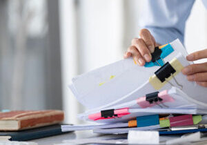 Businesswoman hands working in Stacks of paper files for searching and checking unfinished document achieves on folders papers at busy work desk office